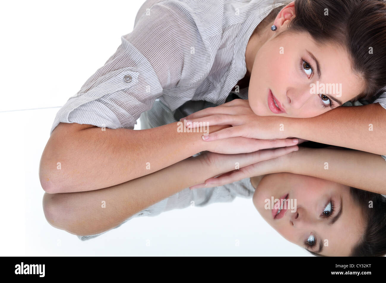 Young woman resting her head on a mirrored surface Stock Photo