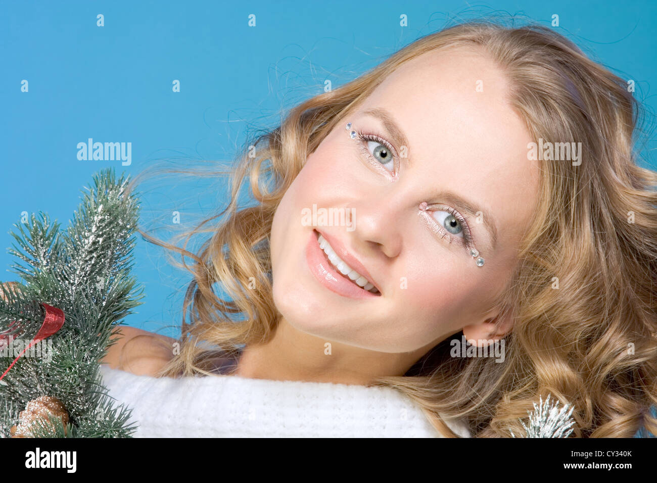 Portrait of mid-aged beautiful blonde female surrounded by branches of decorated Christmas tree Stock Photo