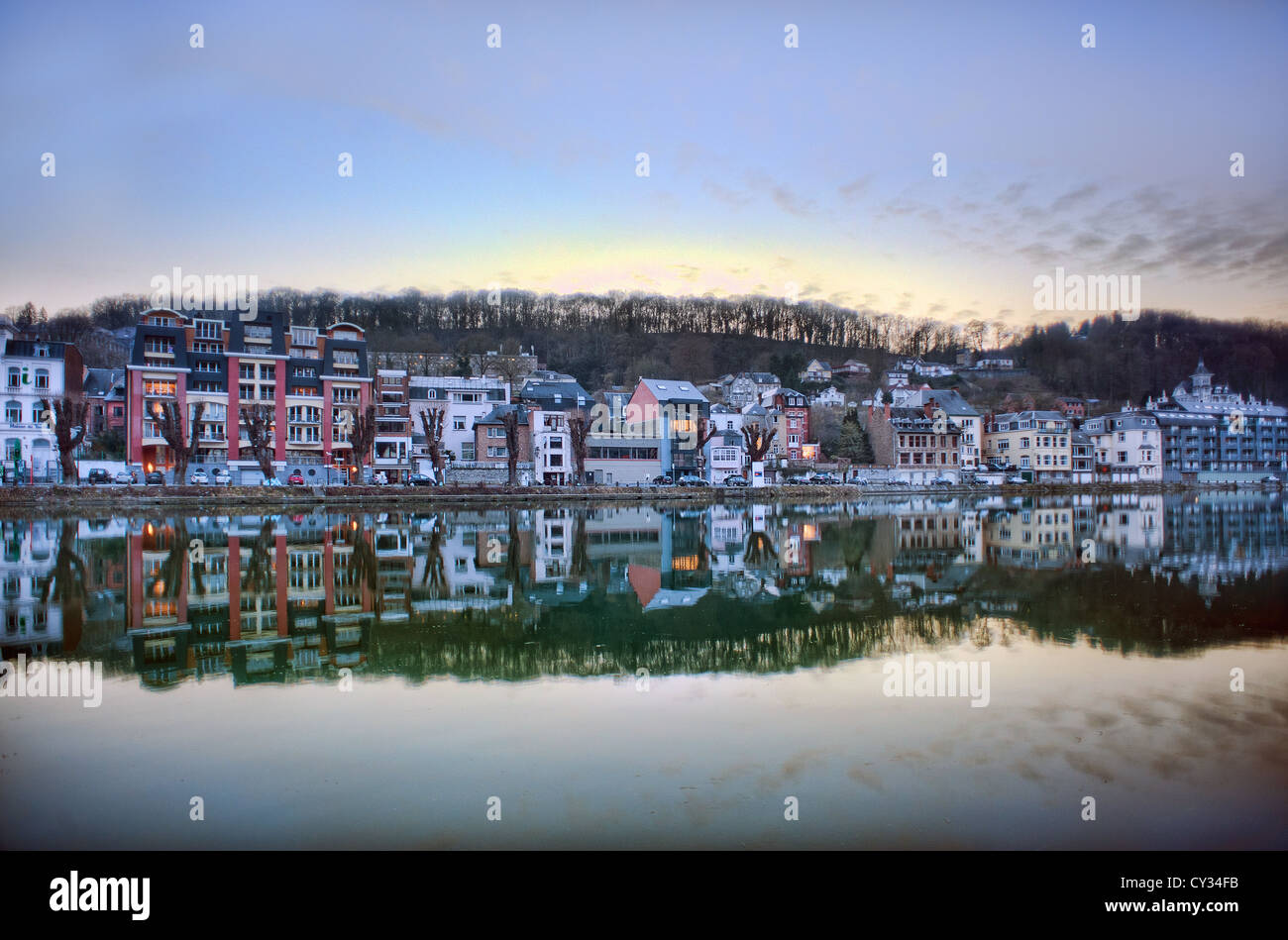 Houses and shops are reflected in the Meuse river at dusk in the Belgian town of Dinant in the Ardennes. Stock Photo