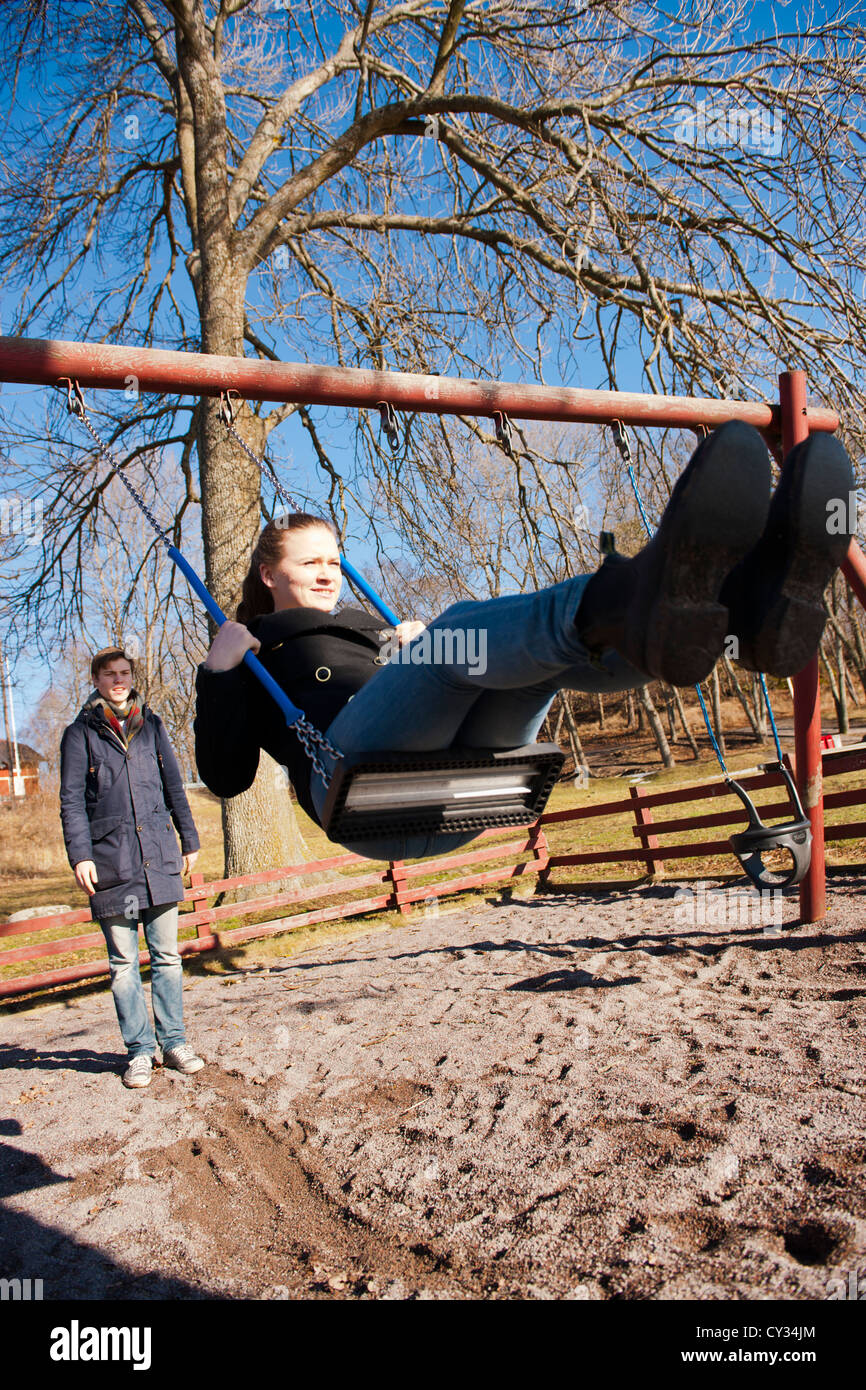 Teenage couple playing in a play ground swing Stock Photo