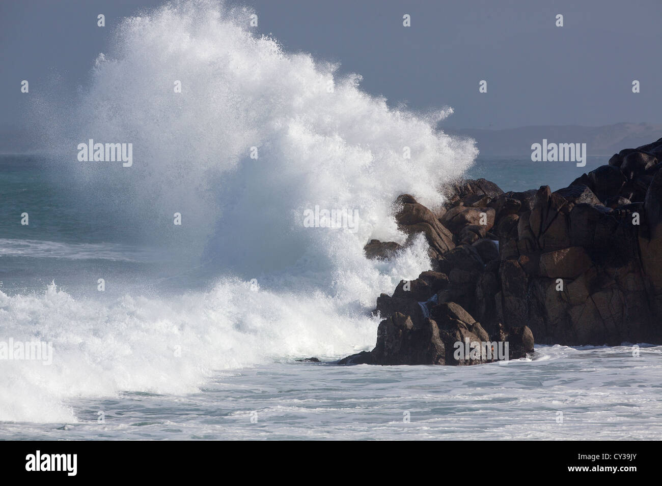 A wave crashes against the rocky California coast. Stock Photo