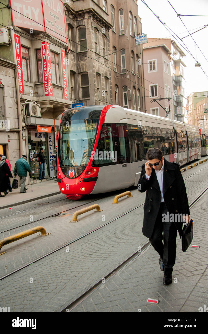 A man on his mobile phone in the Sirkeci district in the old part of Istanbul with T1 tram in the background Stock Photo