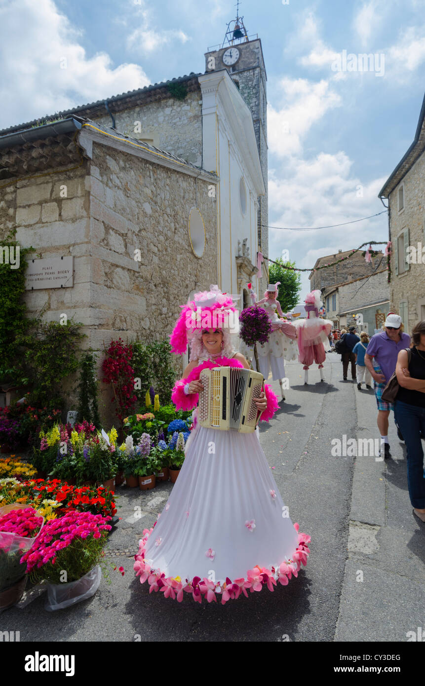 Street performers, Lady accordion player and stilt walkers at the Rose Festival La Colle sur Loup, Provence, France Stock Photo