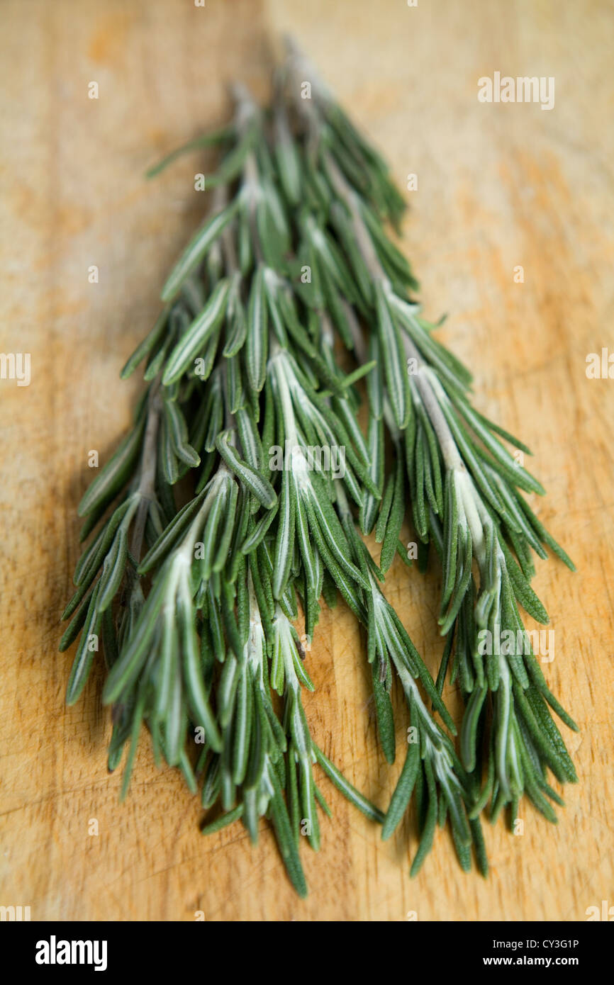 Fresh rosemary on a wooden chopping board. Stock Photo