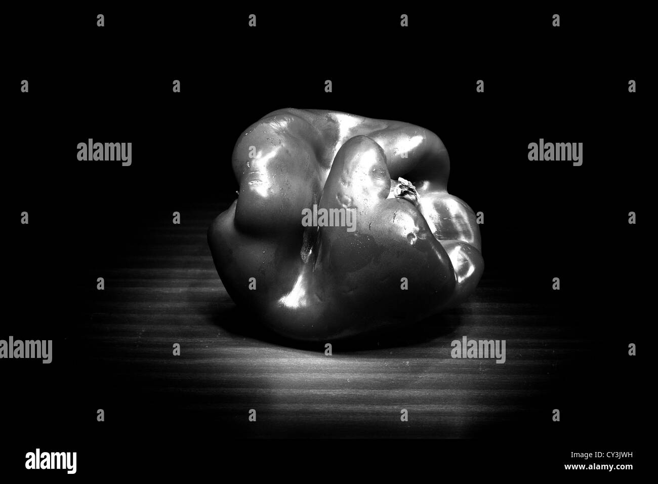 A close up black and white image of a twisted bell pepper