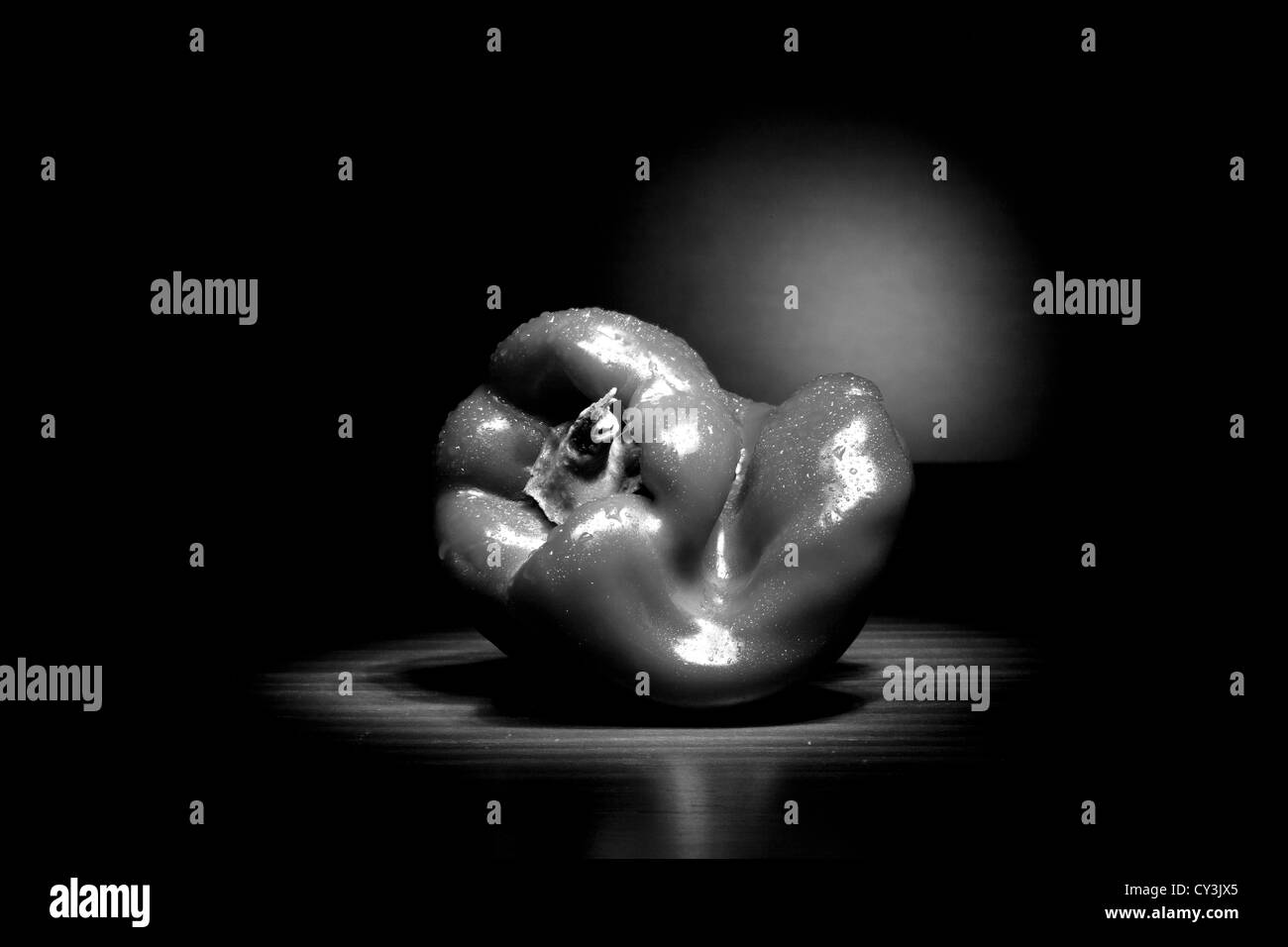 A close up black and white image of a twisted bell pepper