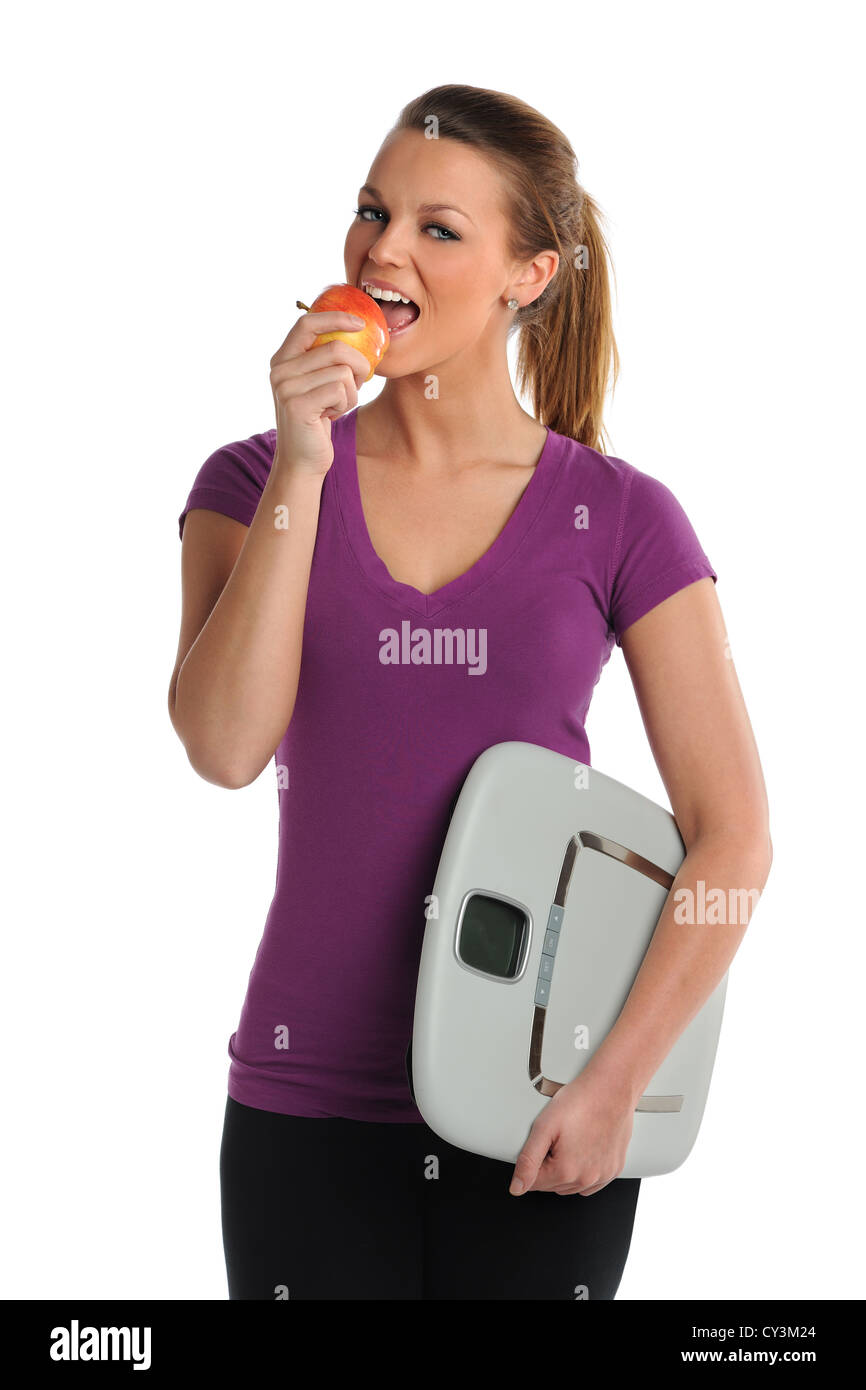 Young woman eating apple and holding scale isolate over white background Stock Photo