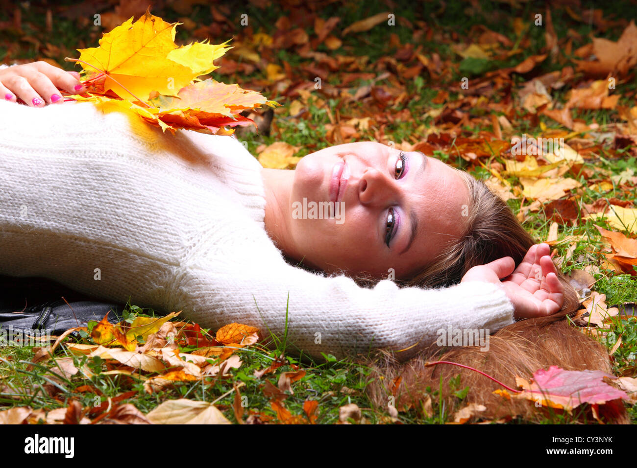 Young woman with autumn leaves in hand and fall yellow maple garden ...