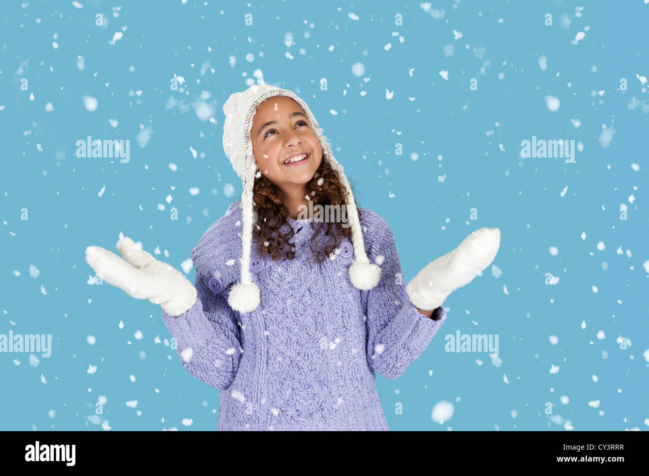 snowing on girl with winter hat and gloves, blue background Stock Photo