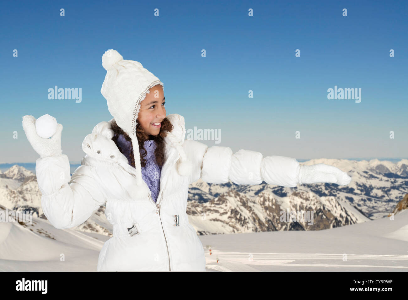 winter fun, girl throwing a snow ball. Mountains in the background Stock Photo
