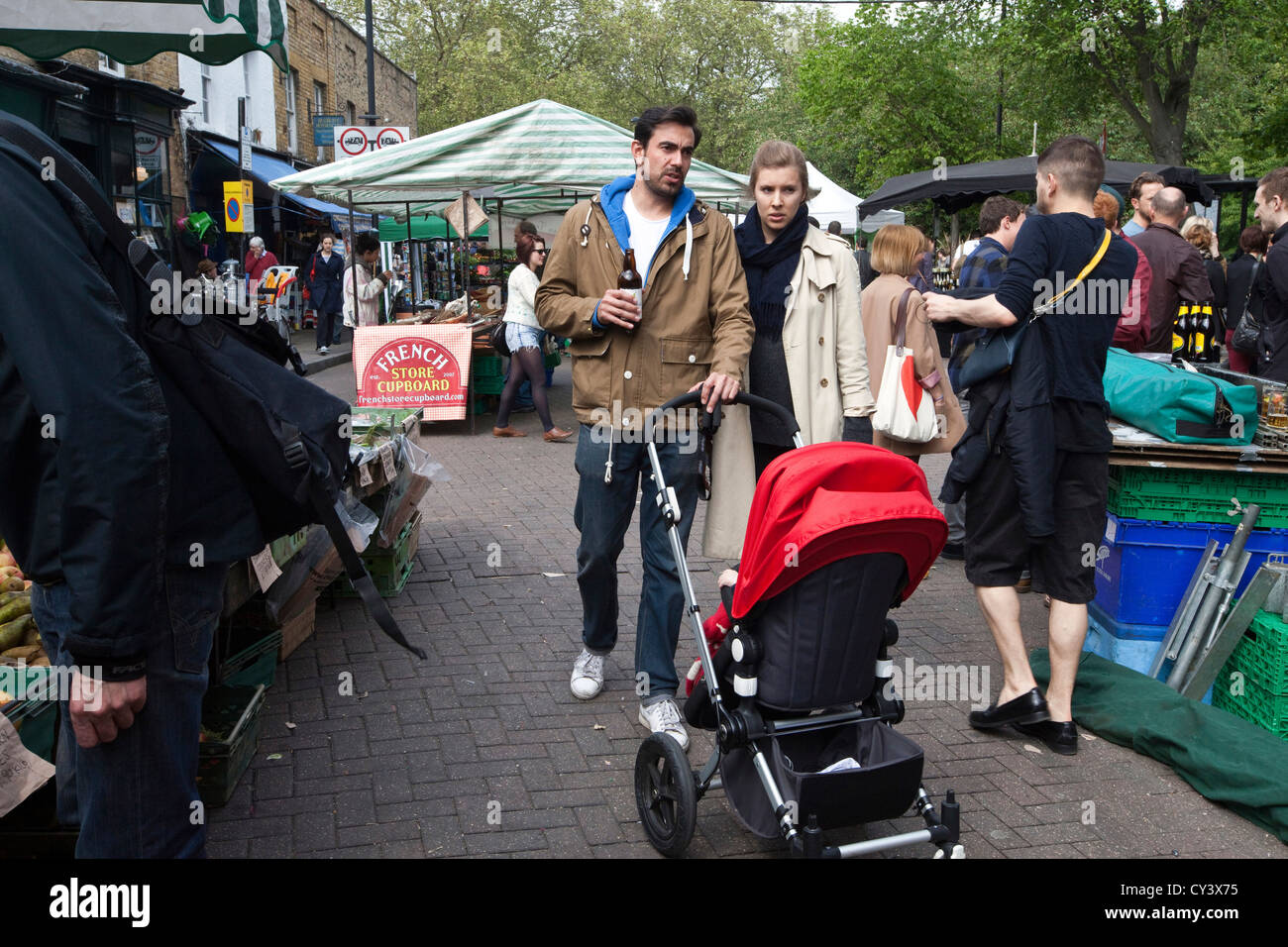 A couple with a pram walk through Broadway Market, London Fields, Hackney, East London, UK Stock Photo
