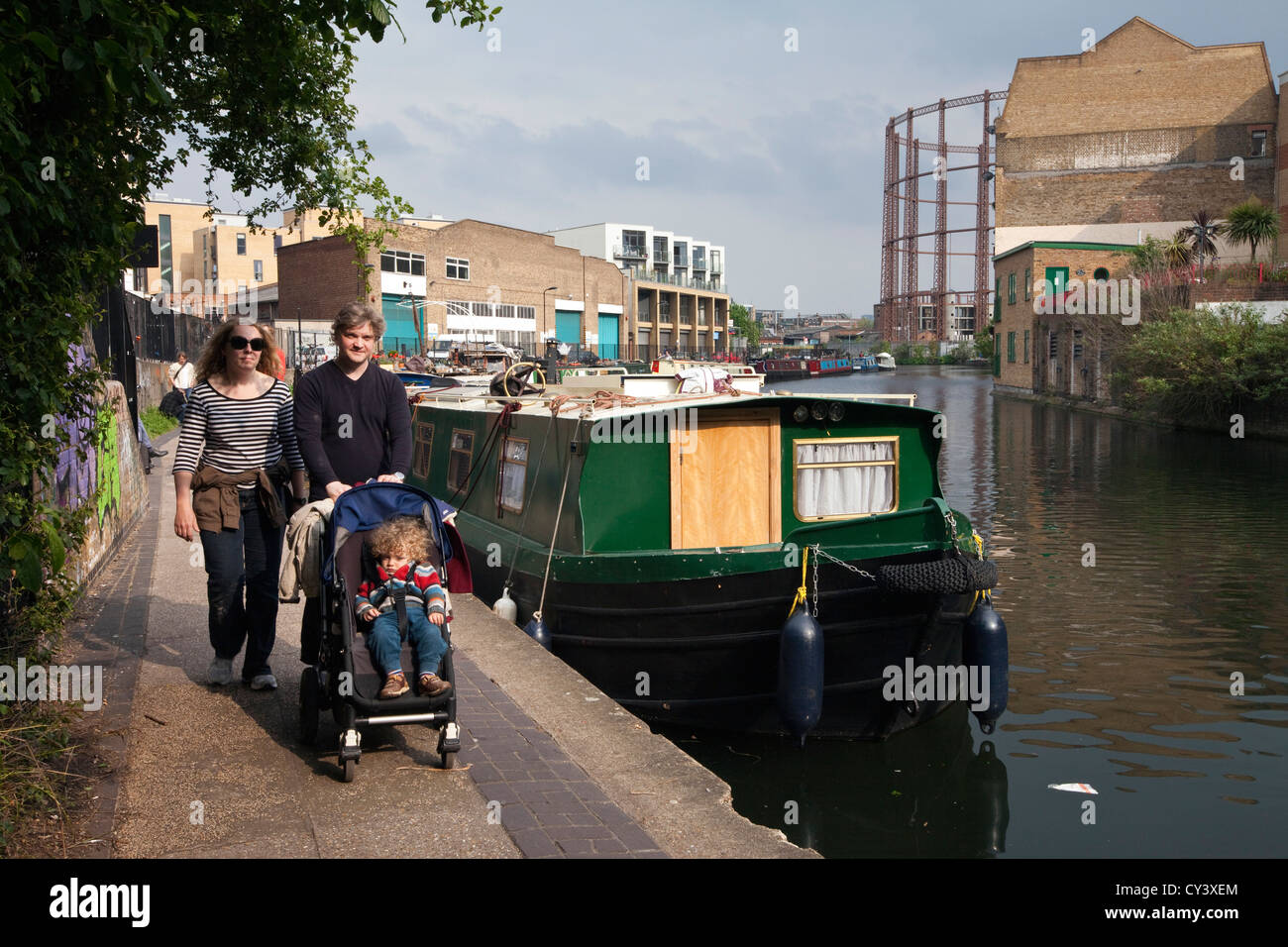 A couple push their child in a pram along the towpath of the Regent's Canal by Broadway Market, London Fields, Hackney, London Stock Photo