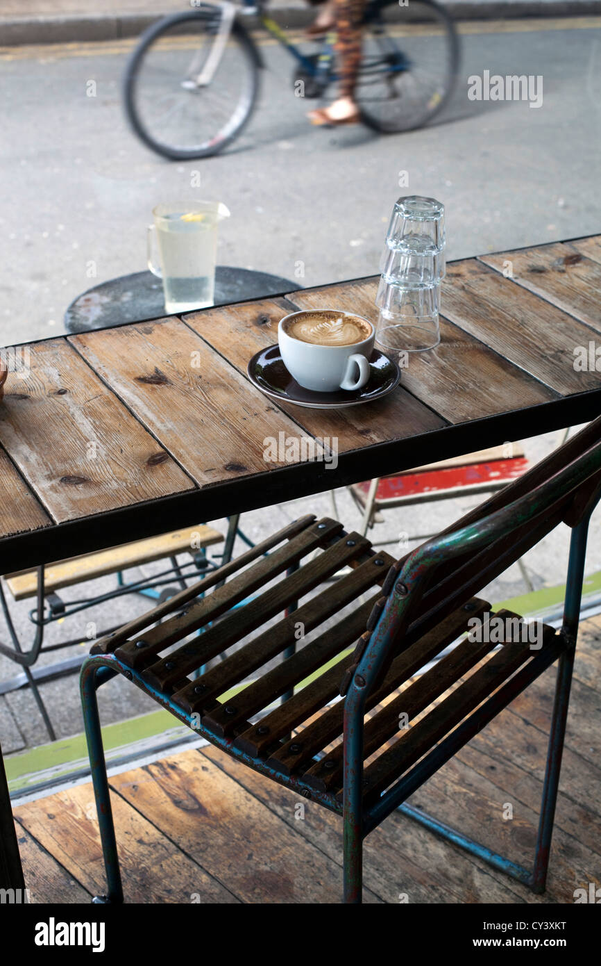 A coffee on the table at L'Eau de la Bouche, an upmarket deli and cafe in Broadway Market, London Fields, Hackney, London UK Stock Photo