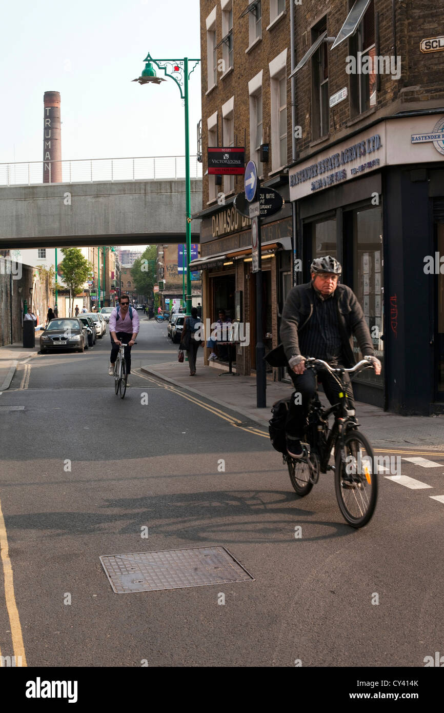 A man cycles down Brick Lane, London, UK Stock Photo