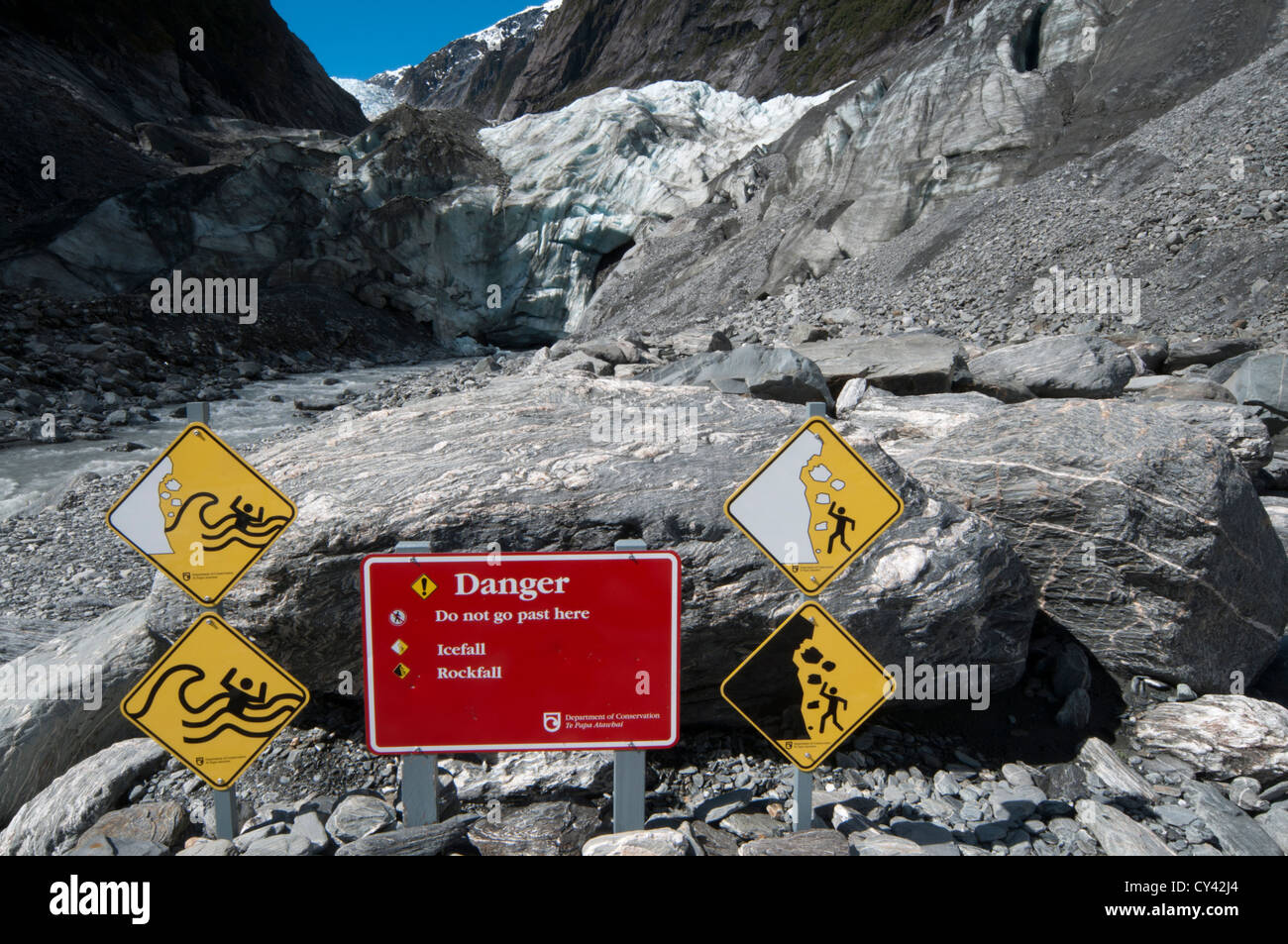 Warning signs show the glacier tongue dangers to hikers and visitors of New Zealand's Franz Josef Glacier.  Warnschilder. Stock Photo
