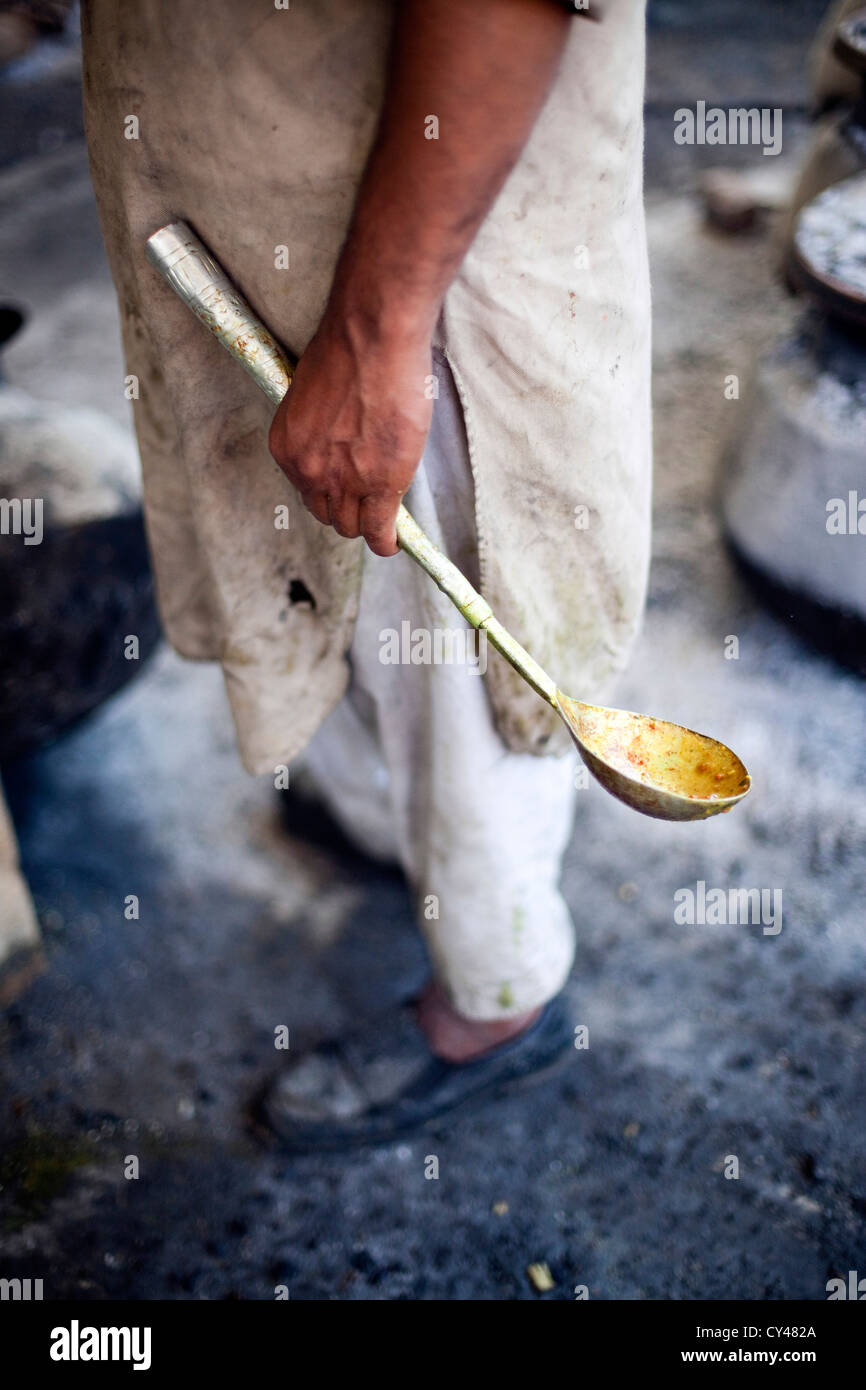 A Waza, a traditional Kashmiri cooks, holds a spoon whilst preparing a Wazwan a Kashmiri feast. Srinagar, Kashmir, India Stock Photo