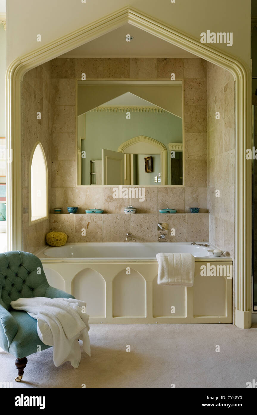Pale blue tufted armchair in bathroom with alcove bath Stock Photo Alamy