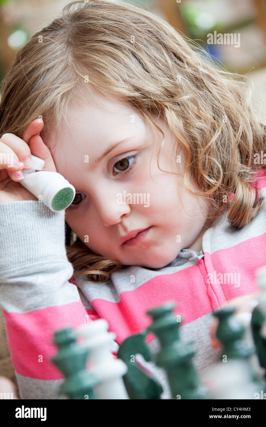 Pretty young British girl aged four years old playing on a chess board