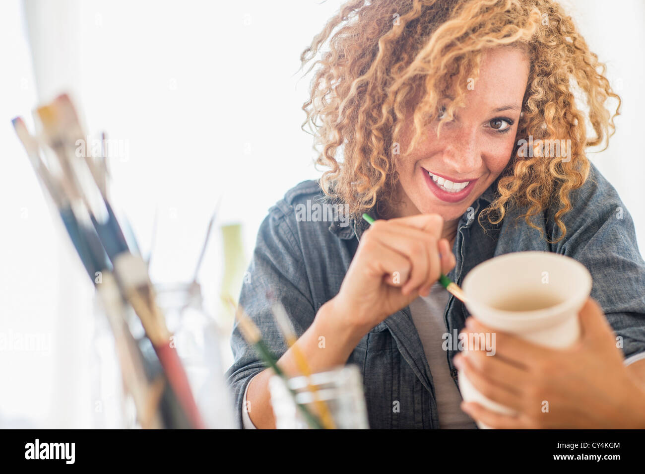 USA, New Jersey, Jersey City, Portrait of female artist painting on ceramics in studio Stock