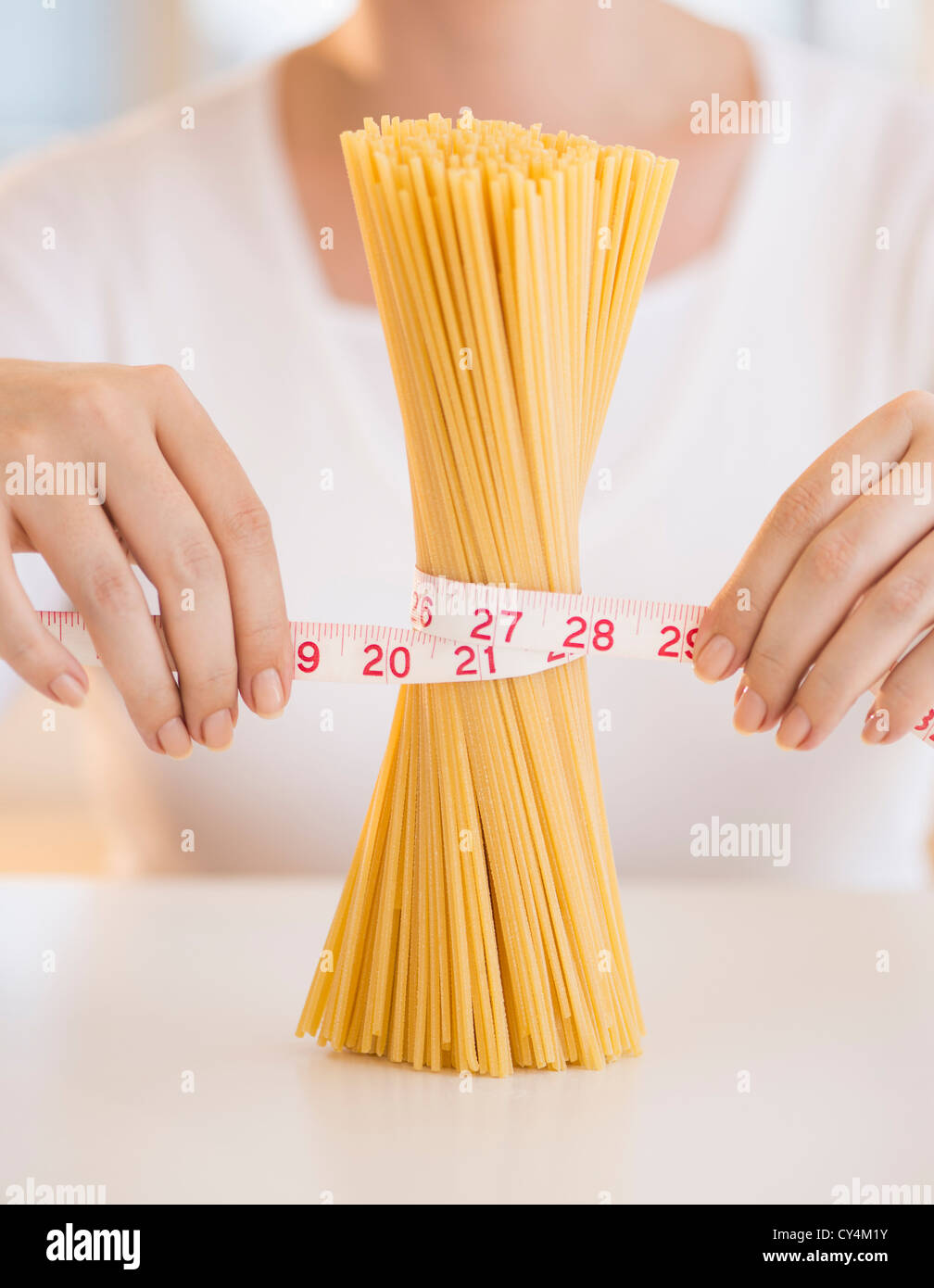 USA, New Jersey, Jersey City, Close up of woman's hands measuring pasta with tape measure Stock Photo