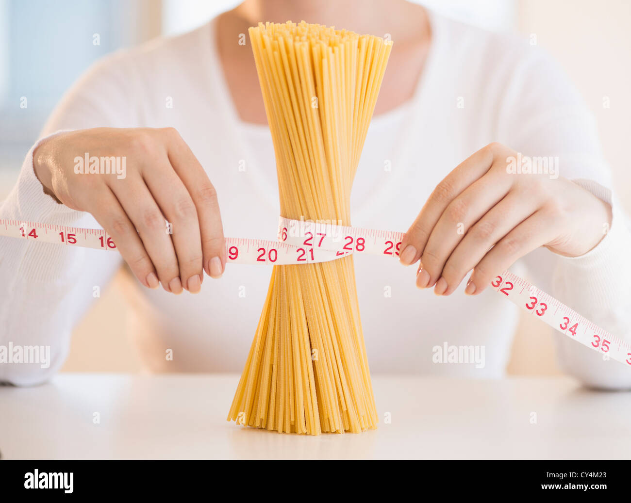 USA, New Jersey, Jersey City, Close up of woman's hands measuring pasta with tape measure Stock Photo