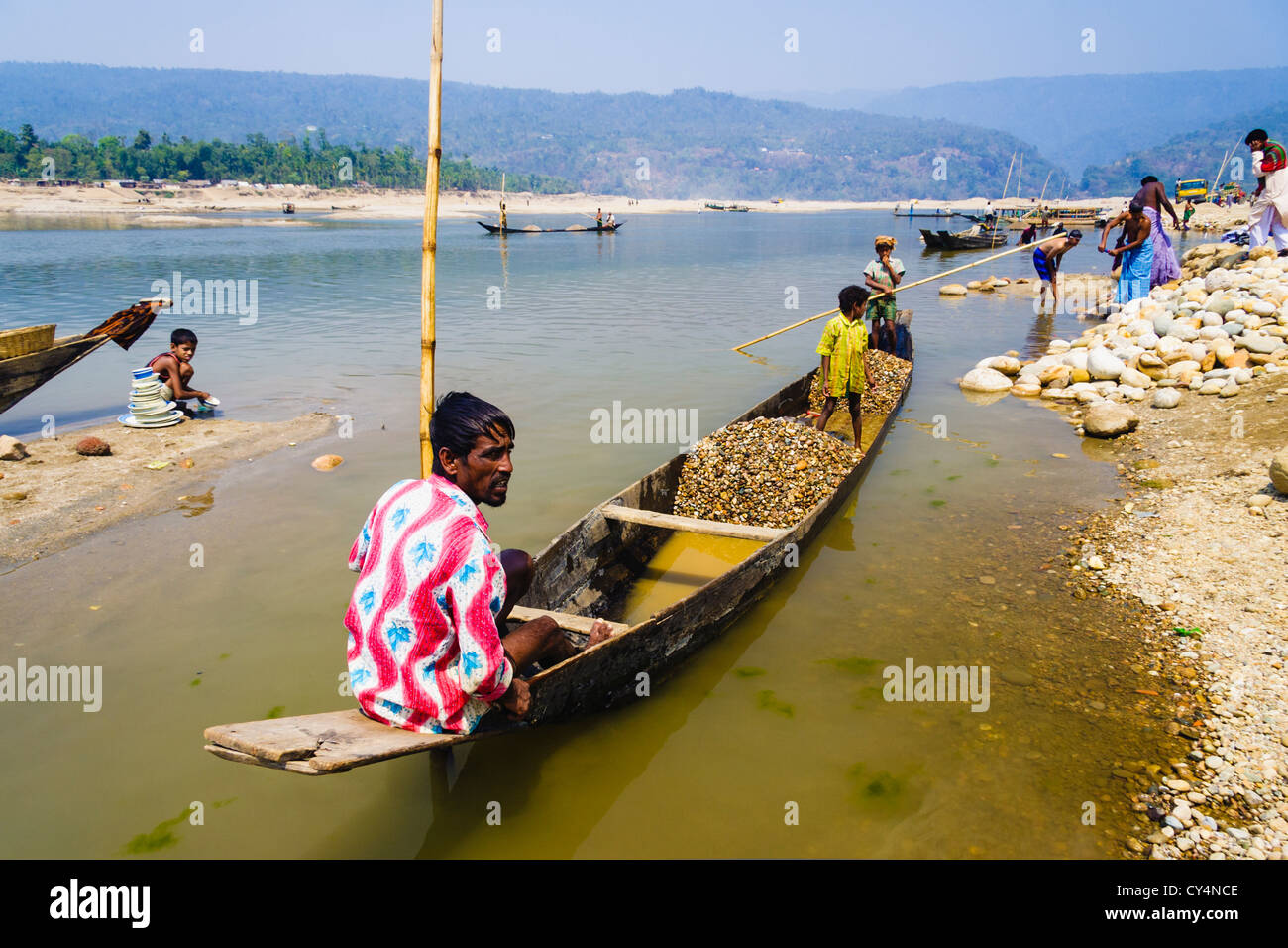 Bangladeshi family on a small boat collecting stones and boulders to be used in construction sites. Jaflang, Sylhet, Bangladesh Stock Photo