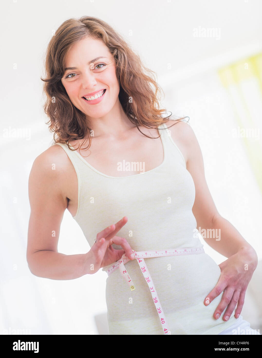 Surprised excess weight caucasian woman wrap measure tape around her waist.  High quality photo image. Stock Photo by ©kazzakova 558018968