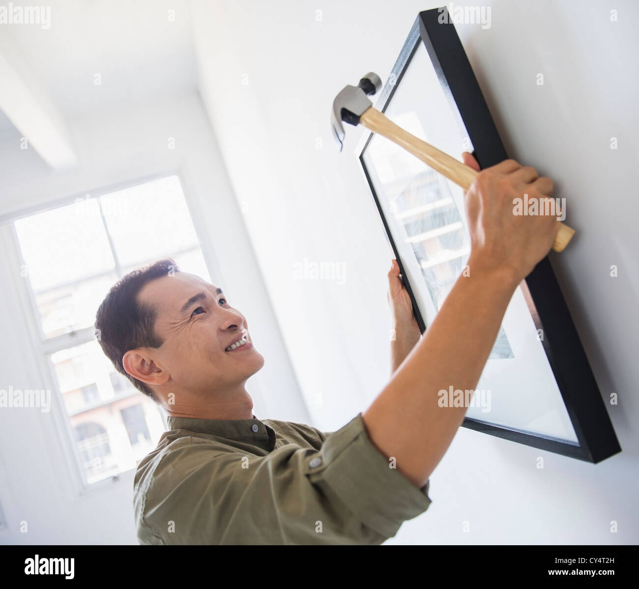 Mid adult man hanging picture on wall Stock Photo
