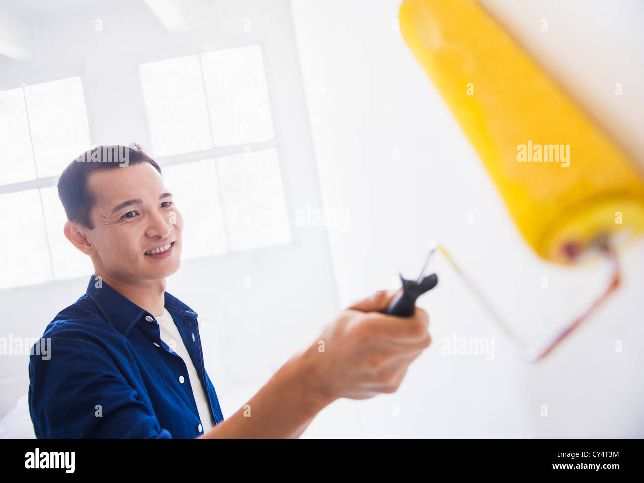 Man painting wall with painting roll Stock Photo - Alamy