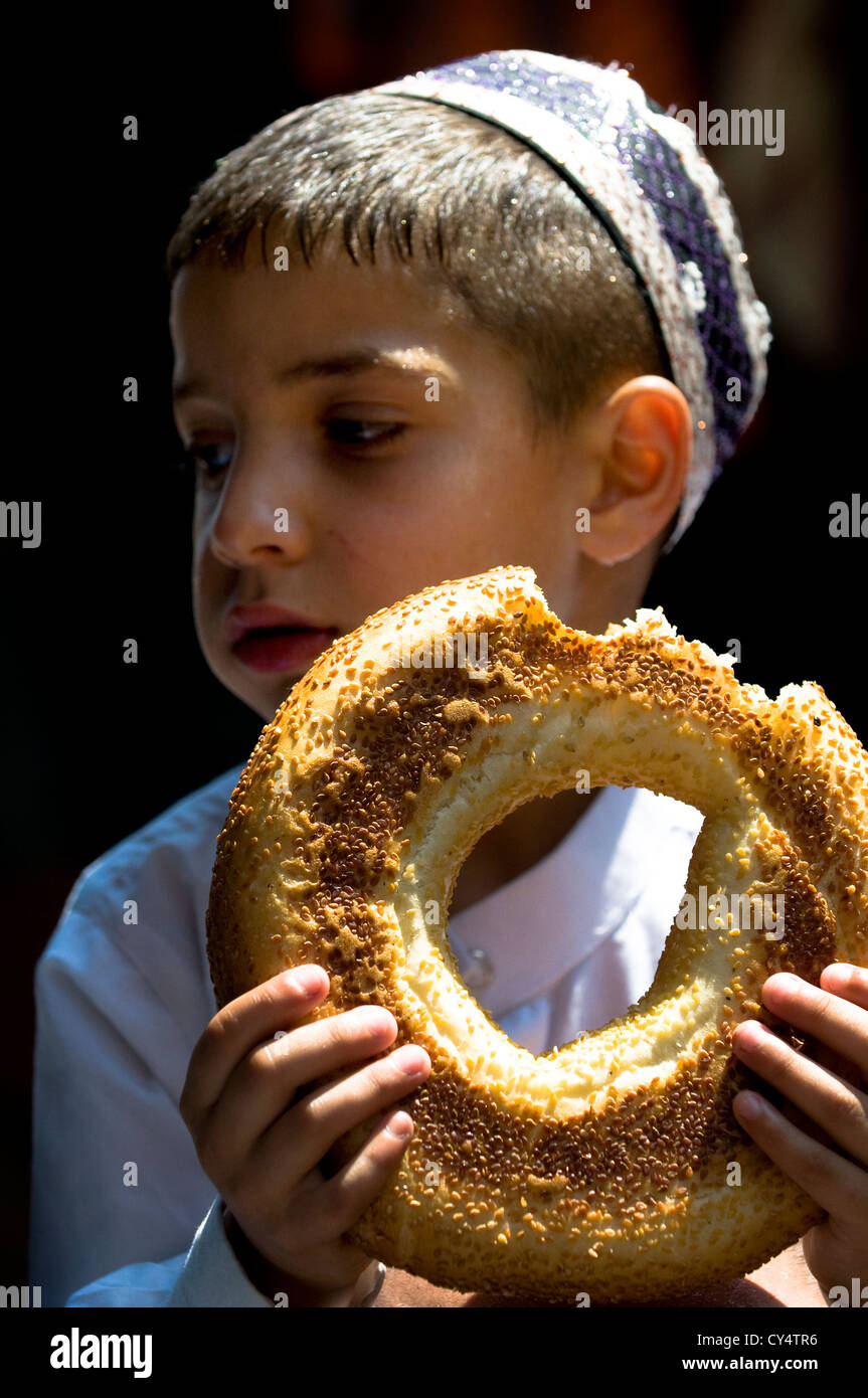 A small Palestinian boy enjoys a bagel bread after the Friday prayers in Al Aqsa mosque. Stock Photo