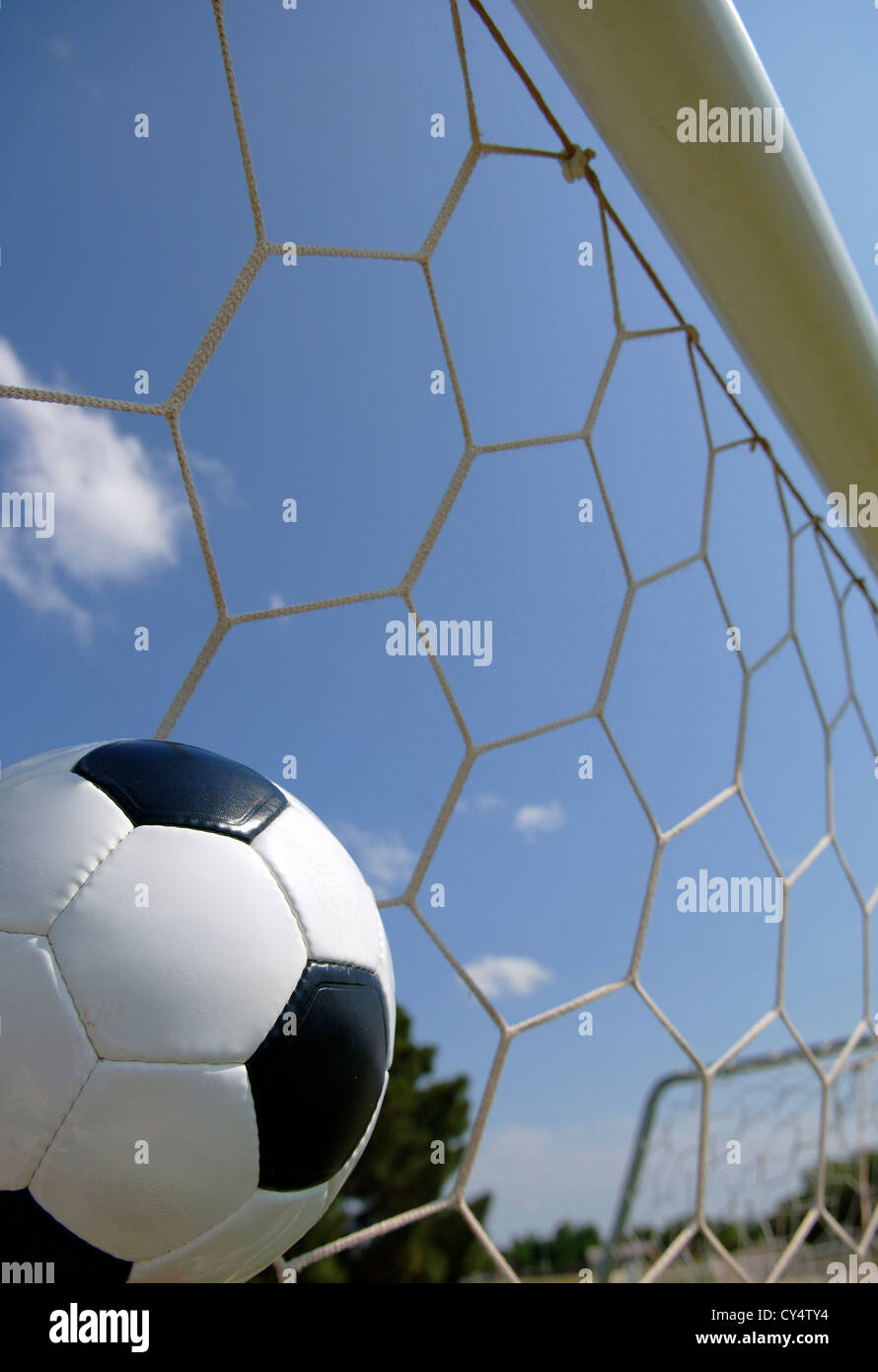 Soccer ball in goal with blue sky background Stock Photo