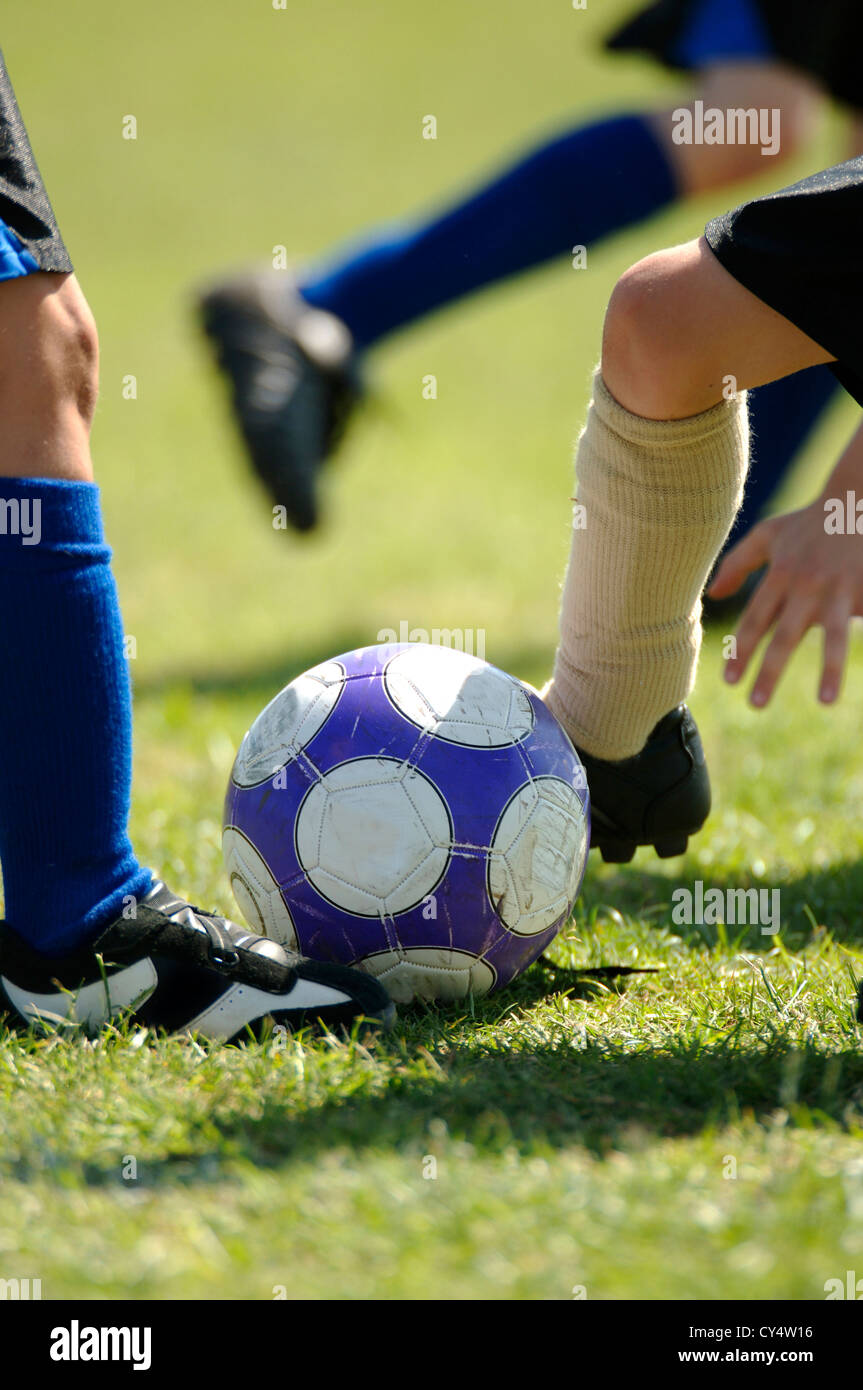 Several set of feet trying to control soccer ball - football Stock Photo