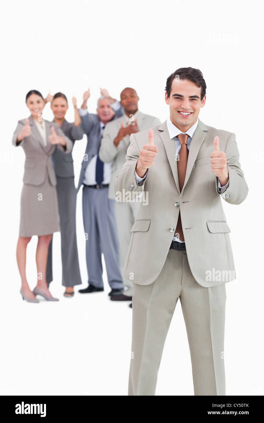 Smiling businessman with team behind him giving thumbs up Stock Photo ...