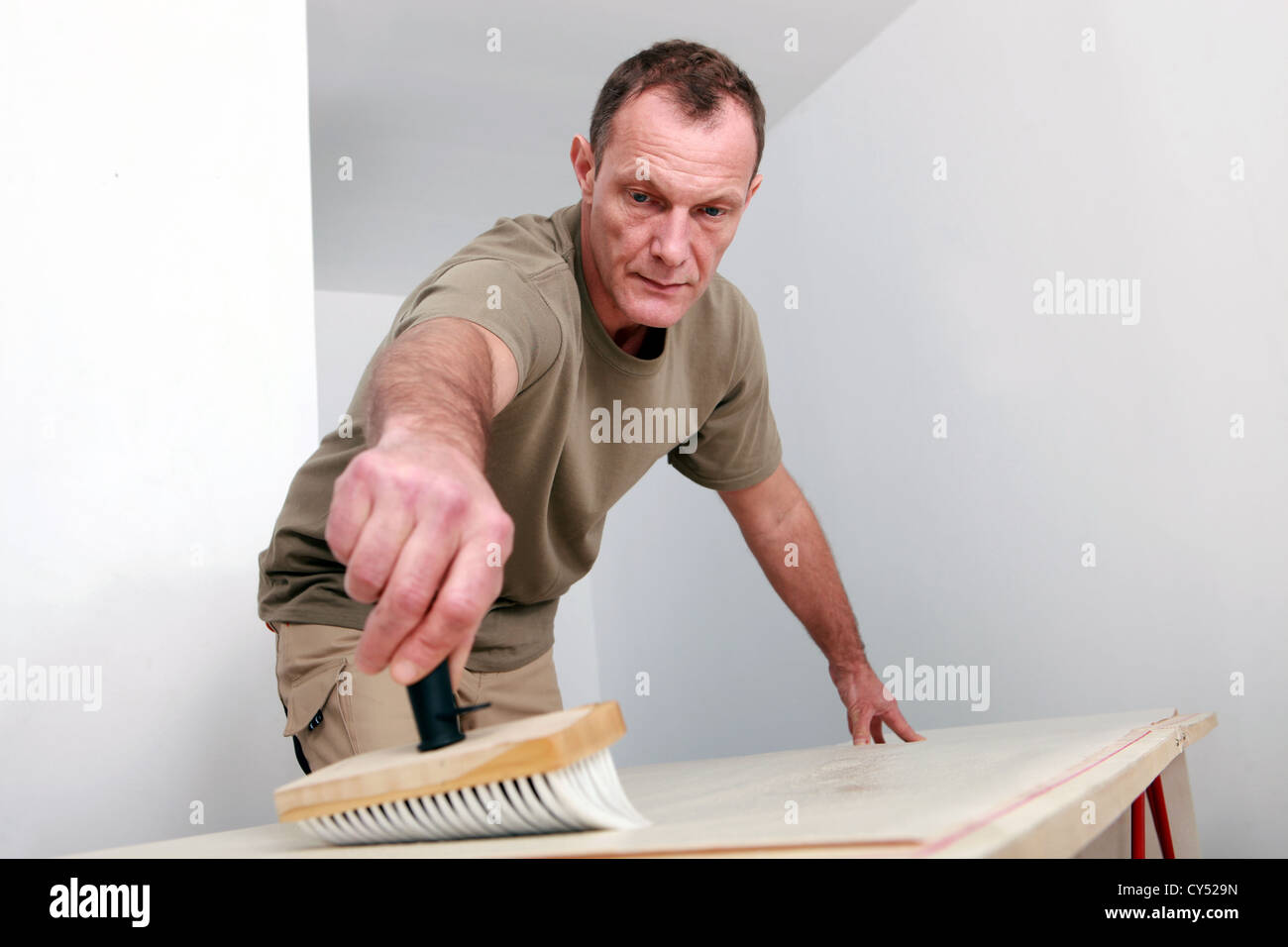 Man sweeping a wooden surface Stock Photo