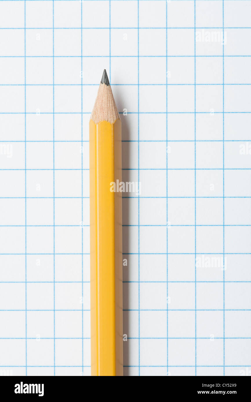 Close up of single yellow sharpened pencil on graph paper Stock Photo