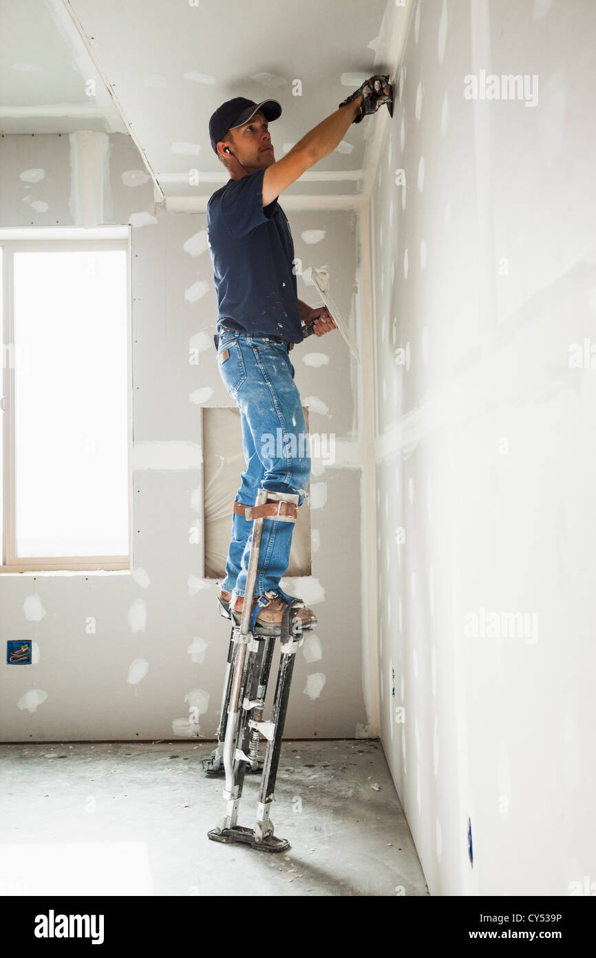 USA, Utah, Lehi, Drywall worker on stilts working on drywall joints
