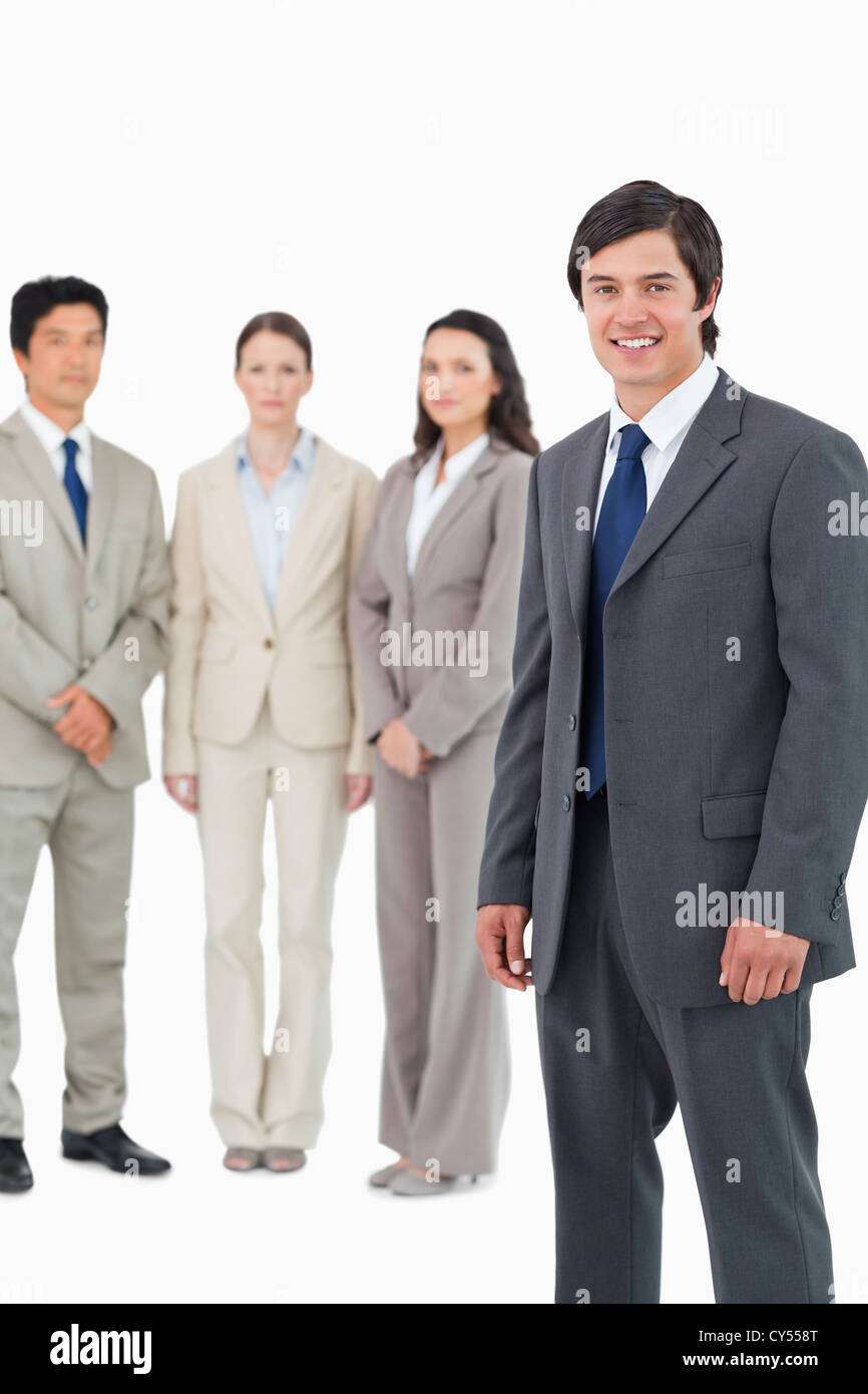 Smiling young salesman with team behind him Stock Photo - Alamy