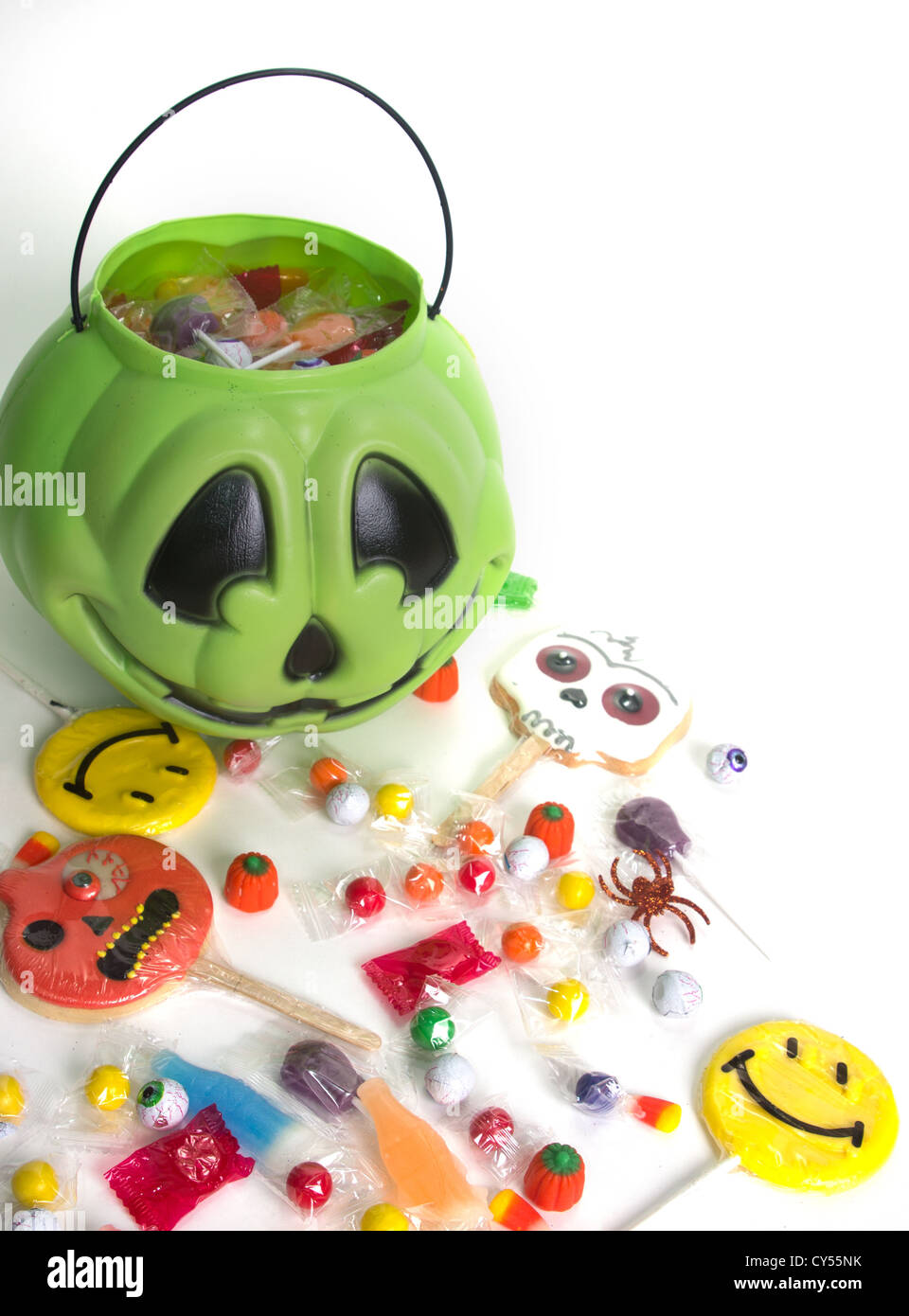 Green pumpkin halloween bucket filled with candy, candy corn, suckers, and cookies. Isolated on