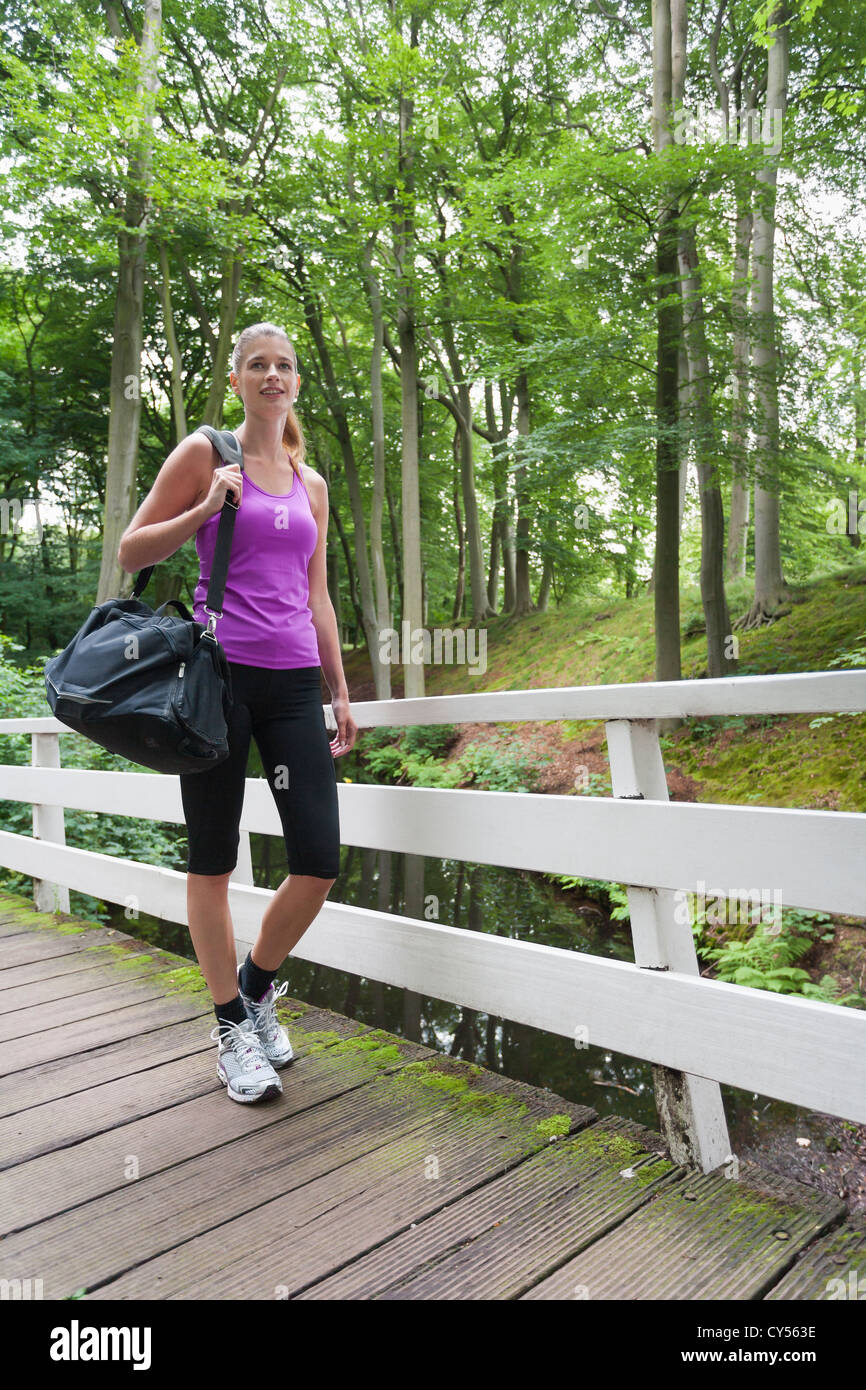 Young woman walking over bridge carrying sport bag Stock Photo