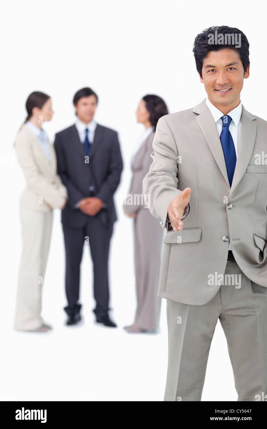 Businessman with colleagues behind him extending his hand Stock Photo ...