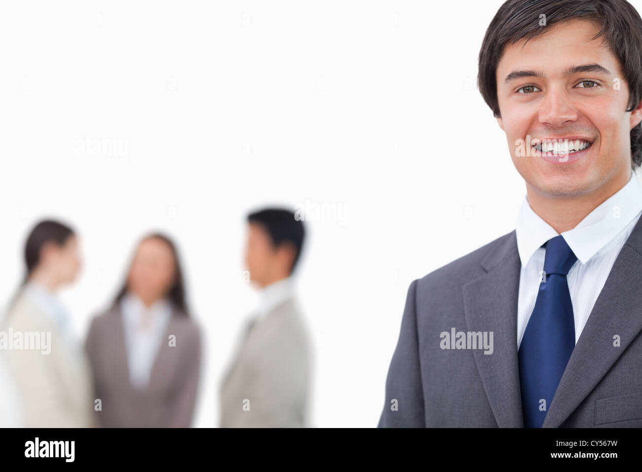 Smiling young businessman with team behind him Stock Photo - Alamy