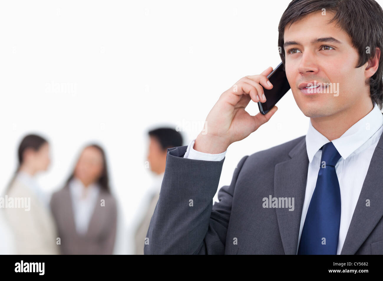 Salesman on his cellphone with team behind him Stock Photo - Alamy