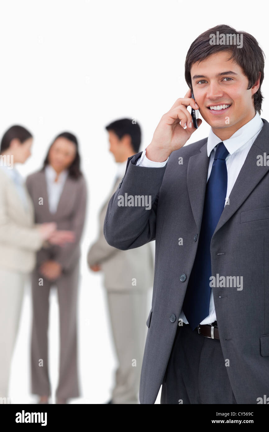 Smiling salesman on cellphone with team behind him Stock Photo - Alamy