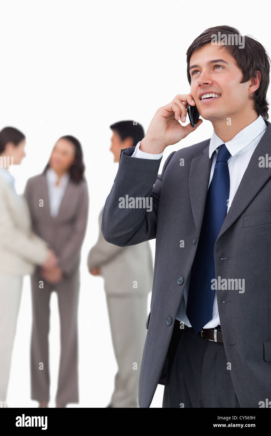 Salesman talking on mobile phone with team behind him Stock Photo - Alamy