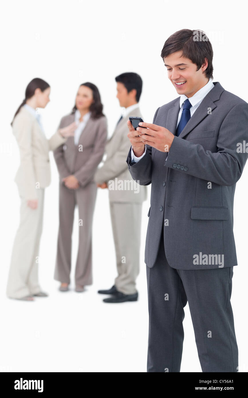 Smiling salesman holding mobile phone with team behind him Stock Photo ...