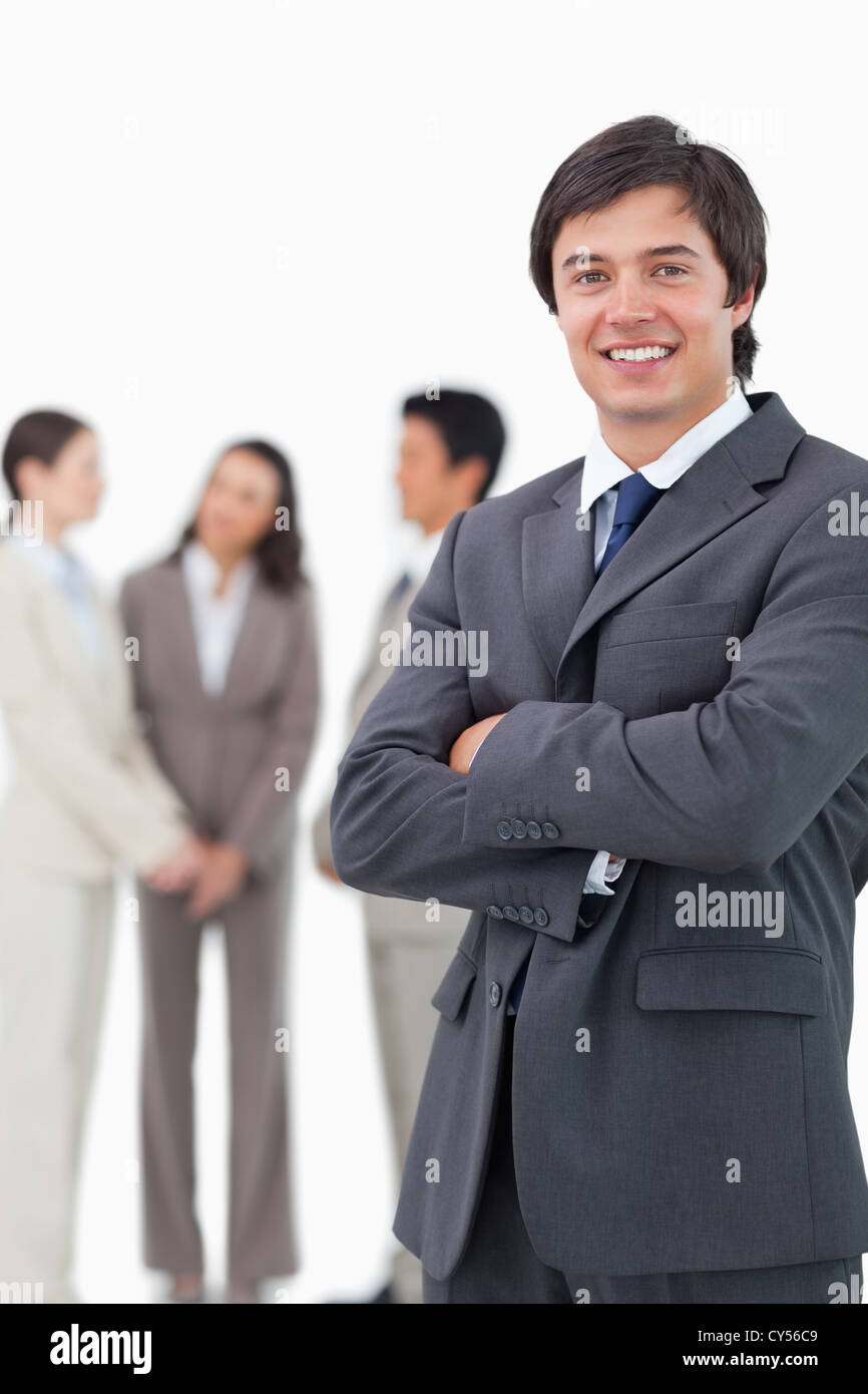 Smiling salesman with arms crossed and team behind him Stock Photo - Alamy