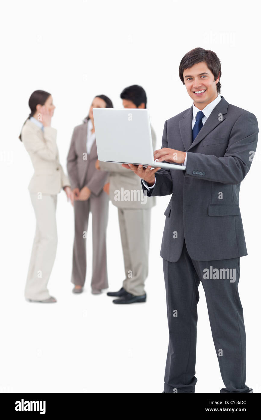 Smiling salesman with laptop and team behind him Stock Photo - Alamy
