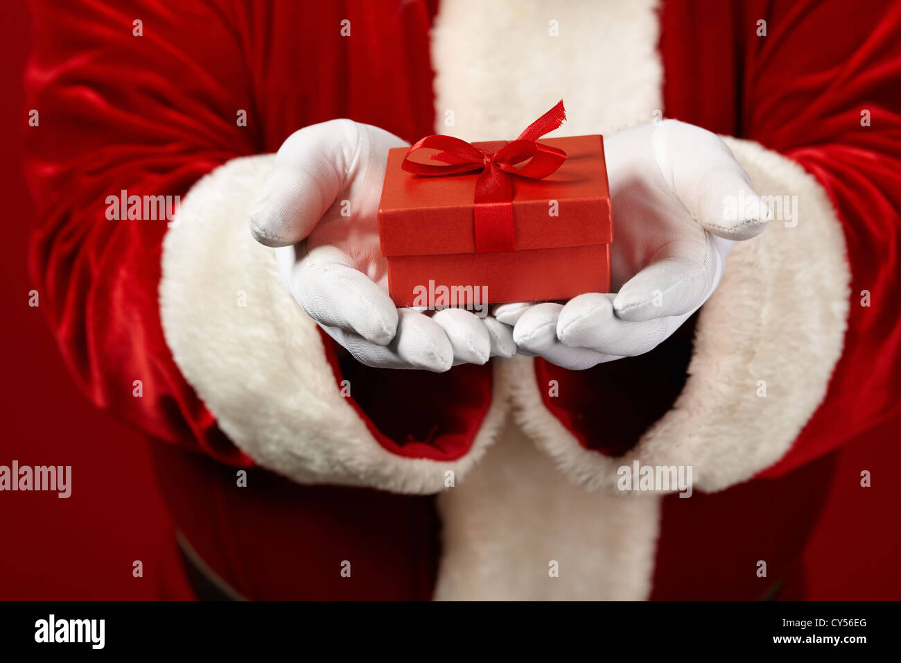 Photo of Santa Claus gloved hands holding red giftbox Stock Photo - Alamy