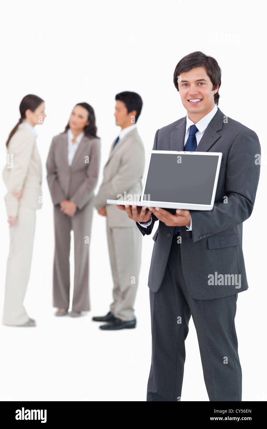 Smiling salesman showing laptop screen with team behind him Stock Photo ...