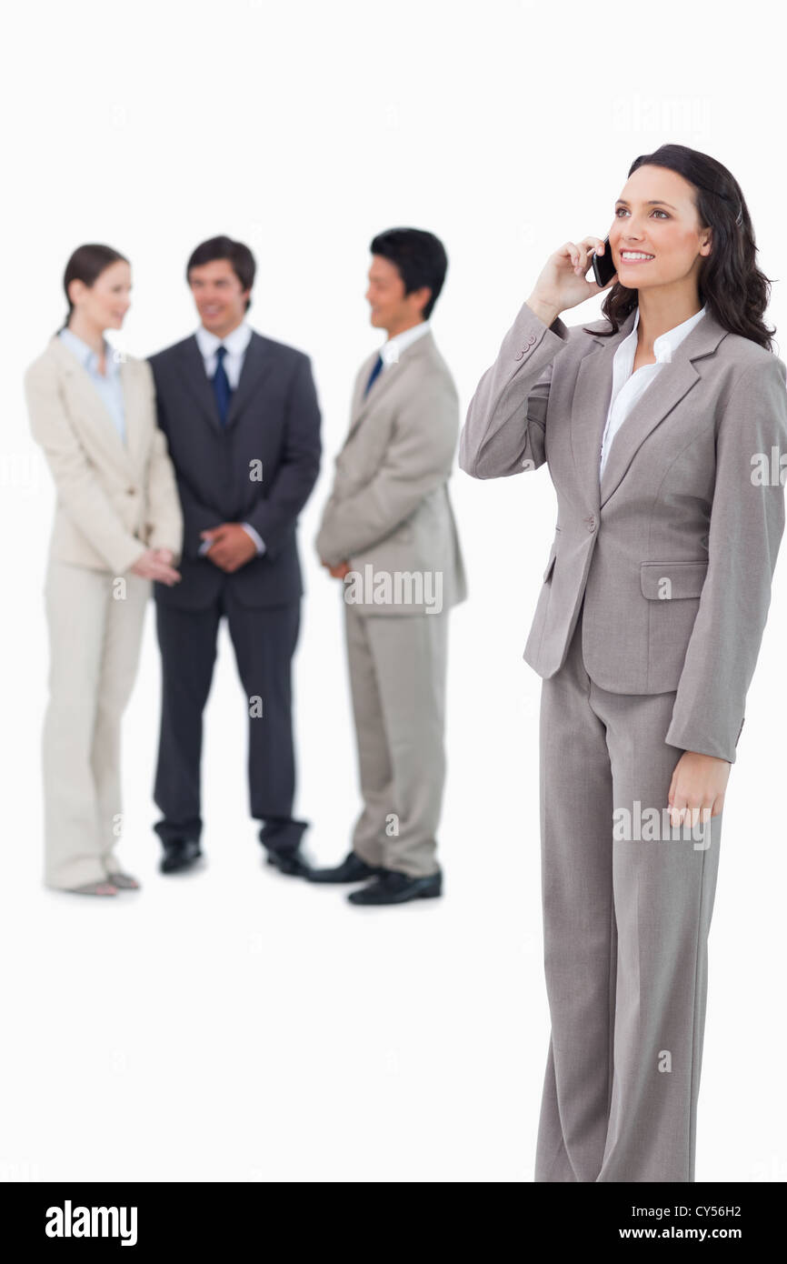 Saleswoman on the cellphone with team behind her Stock Photo - Alamy